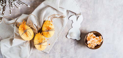 Easter eggs with dried flowers, bowl with marshmallows and bunny on gray top view web banner