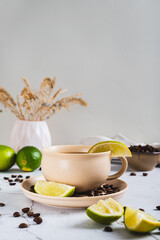 Cold coffee with lime wedges in a cup on the table vertical view