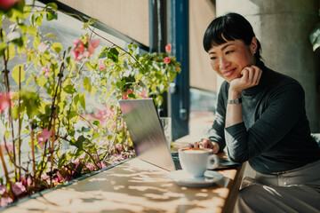 Asian freelancer working on laptop in cafe with flowers