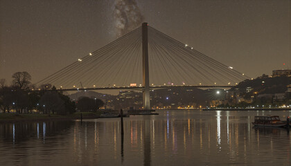 Obraz premium Majestic bridge illuminated at night over reflective waters, urban beauty