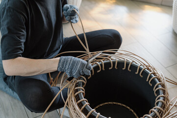 A girl weaves a rattan basket. Handmade work.