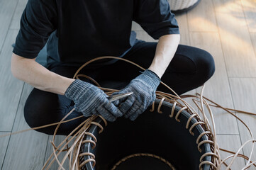 A girl weaves a rattan basket. Handmade work.