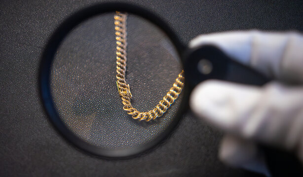 Evaluation of the gold jewelry.The purchase of gold.Pawnshop.A hand with a magnifying glass examines a jewelry bracelet.