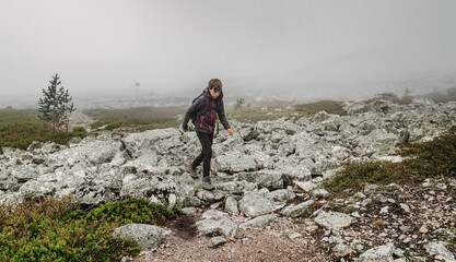 Obraz premium A boy explores the rugged landscape of Dalarna, Sweden, navigating through rocky terrain and green in the mist, enjoying the beauty of nature while hiking