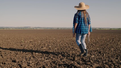 Agriculture, a farmer in rubber boots walks on the plowed land, resting a plot of land after...