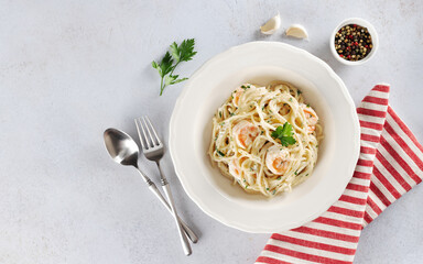 Spaghetti with shrimps, parsley and cream sauce on a white background. Top view. Copy space. Italian food.