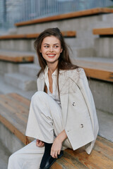 Confident woman in a stylish business outfit sitting outdoors, showcasing a warm smile and...
