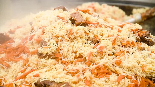 Tasty pilaf in a cauldron on fire in the open air at street food festival