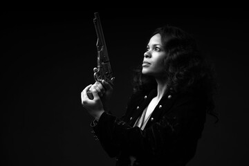 Obraz premium Black and white low key portrait of pretty woman holding vintage revolver