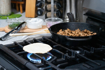 Close-up homemade street tacos with meat, onions, cilantro, and sour cream on a kitchen counter—perfect for food, culture, and celebration-themed concepts.