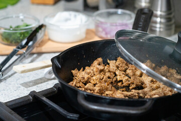 Close-up homemade street tacos with meat, onions, cilantro, and sour cream on a kitchen counter—perfect for food, culture, and celebration-themed concepts.