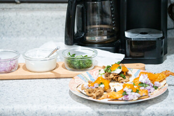 Close-up homemade street tacos with meat, onions, cilantro, and sour cream on a kitchen counter—perfect for food, culture, and celebration-themed concepts.