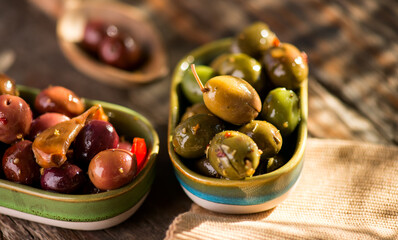 Olives, homemade marinated colorful olives with herbs and spices on rustic table, close up. Healthy Mediterranean vegan food, macro shot 