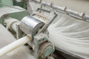 Wool fibers enter a carding machine at a textile plant for further yarn production.