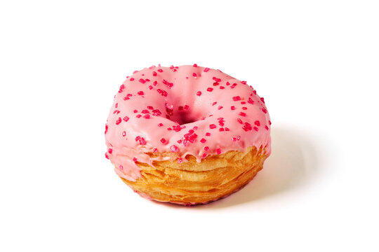 Pink raspberry cronut with strawberry fondant icing and sprinkles on white background