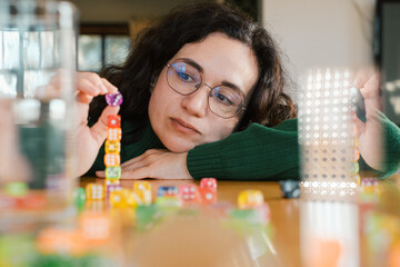 Woman focused on building tower from dice. Balance and patience developed during fun leisure...