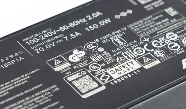 Close-up of laptop charger label with safety markings and specifications