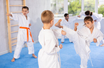 Karate kids in kimono sparring together during their group karate training