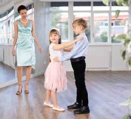 Small passionate ballroom enthusiasts, tween girl and boy practicing graceful waltz routine in...