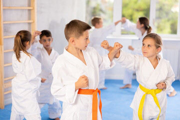 Children students athletes at Academy of martial Arts practice karate and fight opponents in pairs. Obtaining black belt, advanced training, highest dan of martial arts. Sport to max.