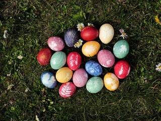 Colorful Easter eggs dyed with store-bought colors. Plants and nets create delicate patterns on the vibrantly colored eggshells.