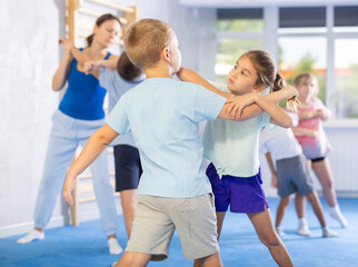 Naklejka premium Children train in pairs to strike and reflect blows of enemy. Self-defense training and Krav Maga principles