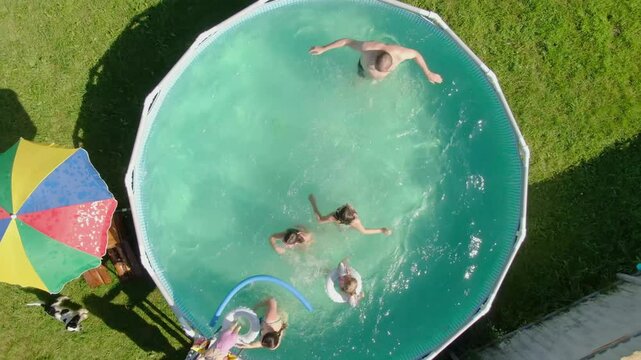 A cheerful company is having fun in the pool of a country house. Slow motion. High quality 4k footage