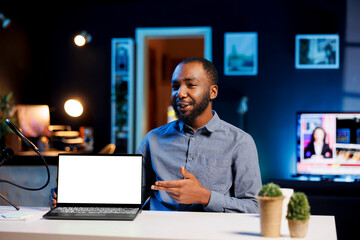 African american man filming himself watching internet videos on mockup laptop requested by...