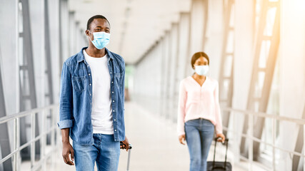 Post-Lockdown Travels. Happy African People In Medical Masks Walking With Luggage At Airport...