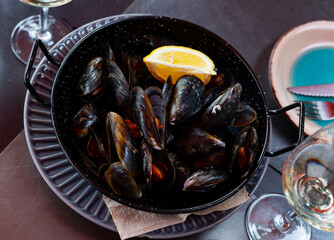 Portion of steamed mussels served on table with piece of lemon