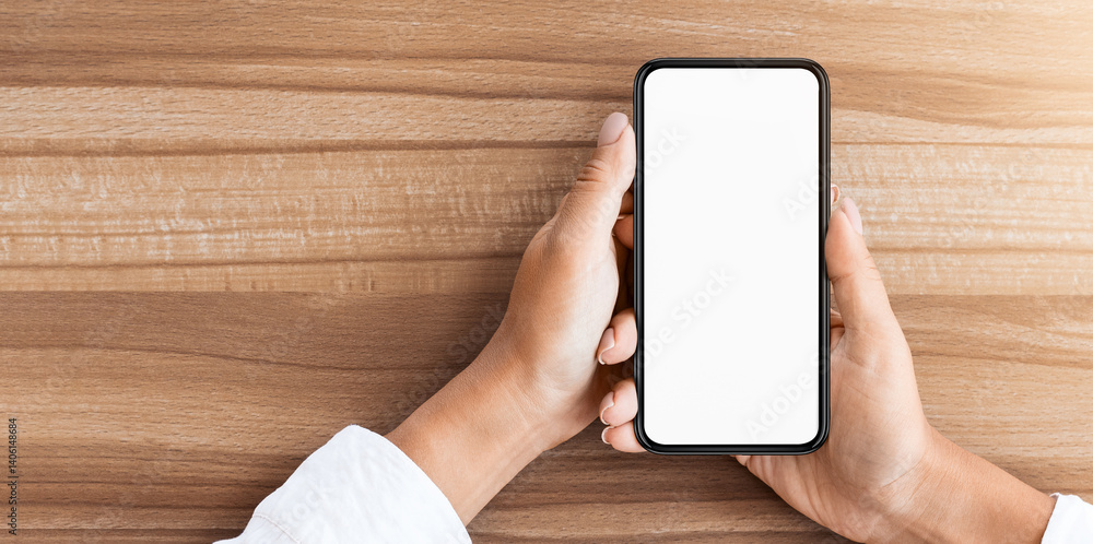 Poster mock up image of hand holding cell phone with isolated blank white screen, wooden table in the backg