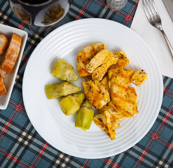 Traditional Spain cuisine, roasted chicken fillet and artichokes on a white plate