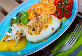 Grilled sepia served on plate with Bulgarian pepper and boiled sweet potato
