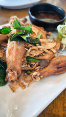 Fried chicken wings in a white plate on a wooden table decorated with orchids.