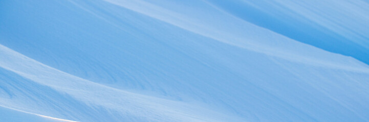 Snow texture. Wind sculpted patterns on snow surface. Wind in the tundra and in the mountains on the surface of the snow sculpts patterns and ridges. Arctic, Polar region. Winter panoramic background.