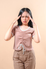 Young woman touching her head with closed eyes, expressing discomfort and pain. Her facial...