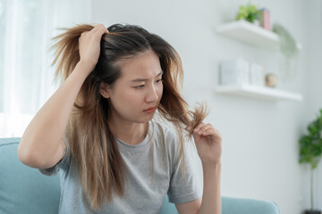 Asian woman very sad and upset looking at damaged hair, hair loss, hair thinning problem, vitamin...
