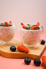 Healthy Chia Pudding in a Glass with Fresh Berries on Pink Background. Chia Pudding with Blueberries and Strawberries. 
Super food. Detox, diet, body cleansing