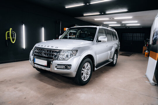 Mitsubishi Pajero in silver color parked inside professional detailing studio with bright LED lights and modern interior &ndash; ideal for showcasing car detailing, protection or advertisement visuals.