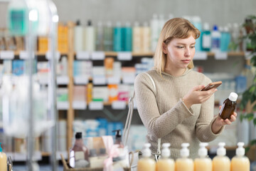 Selective young woman scanning barcode on bottle of syrup held in hand in drugstore