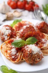 Delicious pasta with meatballs, basil and cheese on white table, closeup