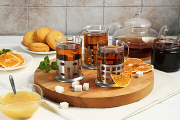 Glasses of tea in metal holders served on white wooden table