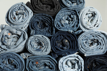 Different stylish rolled jeans on light background, closeup