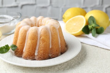 Delicious lemon cake with glaze, mint and citrus fruits on light textured table, closeup