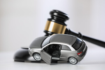 Auto accident law. Toy car and judge's gavel on white table, closeup