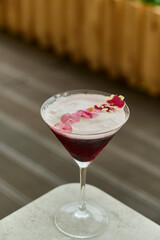 Cocktail in martin with berries on table with city in background