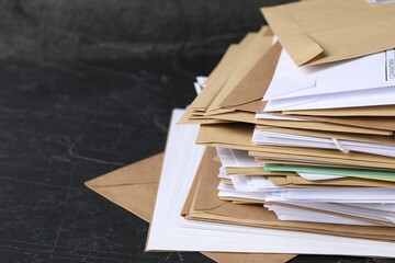 Post office. Stack of different paper envelopes on black table, closeup. Space for text