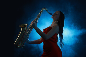 Professional musician playing saxophone on dark background with blue light and smoke