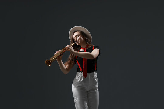 Musician playing soprano saxophone on grey background
