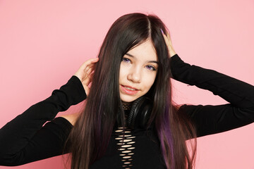 Fototapeta premium Teenage girl with headphones posing on pink background. Makeup and clothes in anime style
